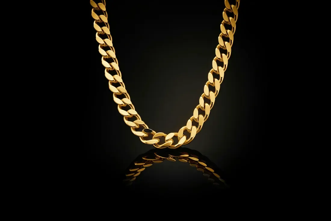 Gold curb chain on black with a soft reflection